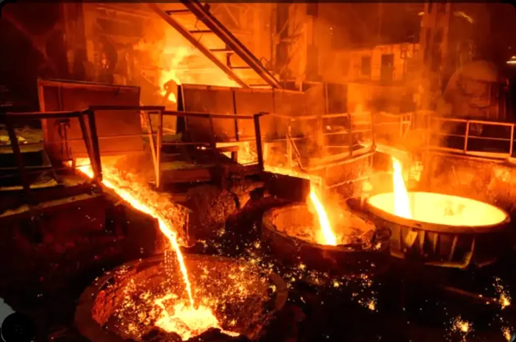 Molten metal pouring inside a steel foundry where high-temperature welding gloves protect workers from radiant heat and molten metal splashes.
