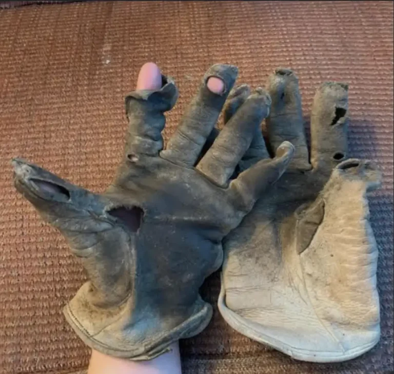 Extremely damaged leather welding gloves with multiple holes exposing the user's fingers.