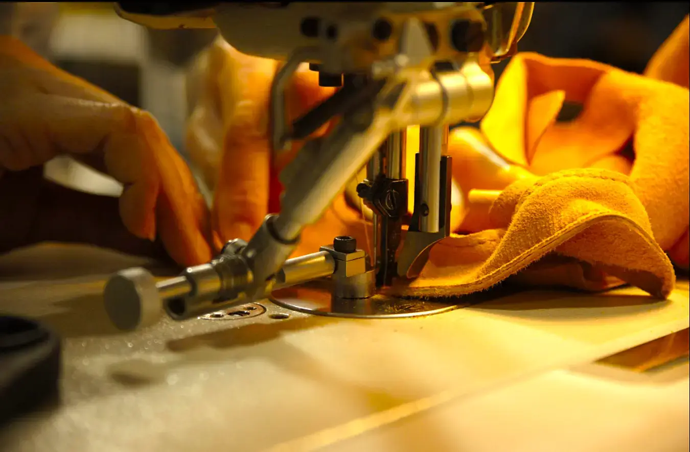 Industrial stitching machine assembling leather safety gloves at ARASWELD factory